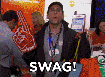 Michael Scott from The Office holds a bunch of bags and a foam finger and saysm “Swag! Stuff we all get.”