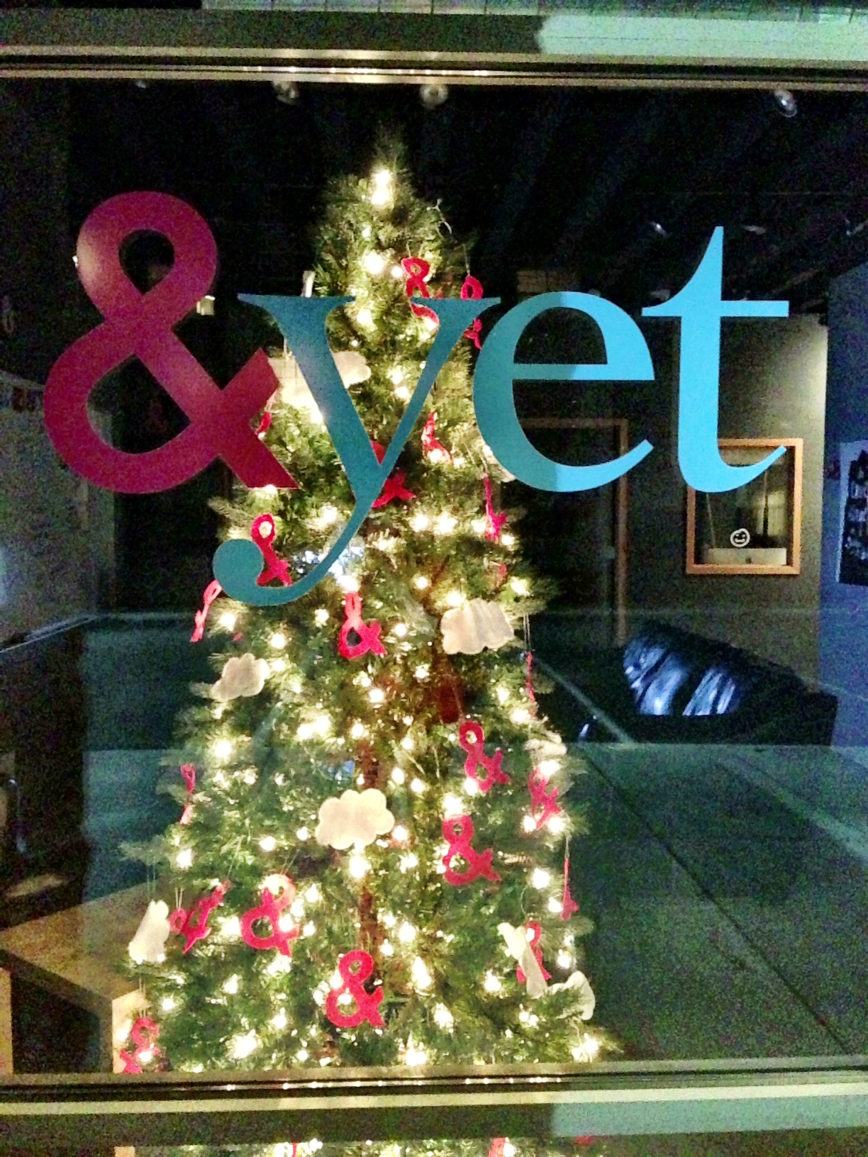 a christmas tree decorated with ampersands behind the &yet logo