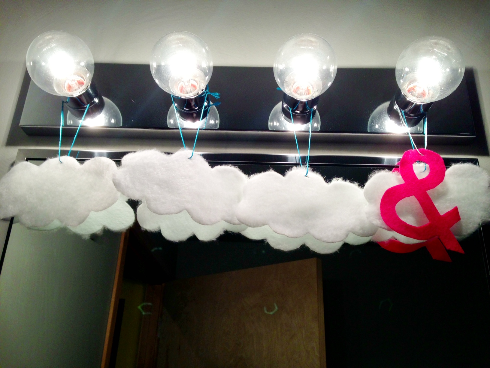 cloud and ampersand felt ornaments hanging from a row of lights